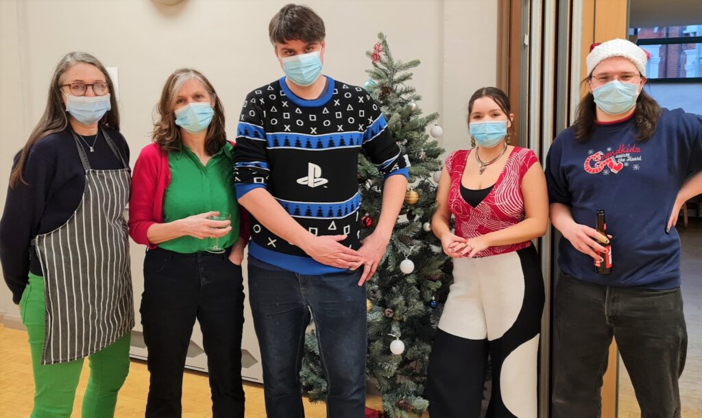 Five volunteers, wearing face masks, standing by the Christmas tree in the Main Hall