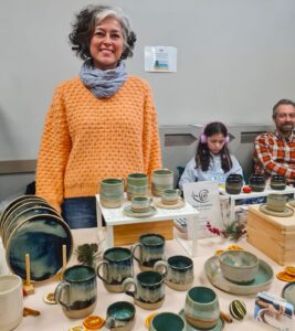 A woman standing behind a table of ceramic tableware