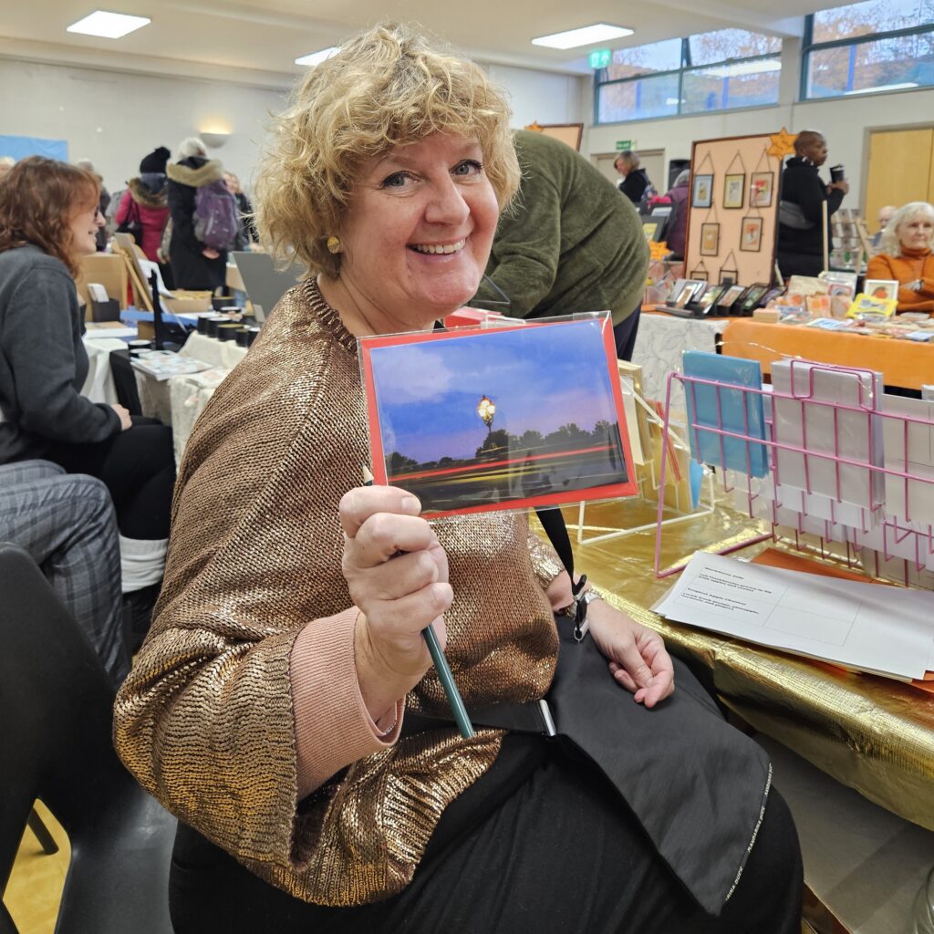 Woman wearing a brown top holding a hand made greeting card