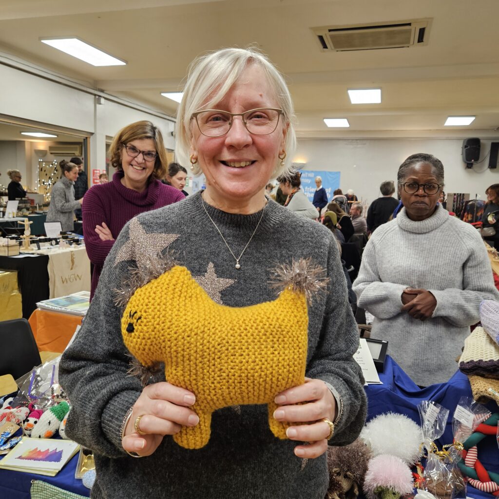 Women with a grey jumper holding a yellow knitted soft toy